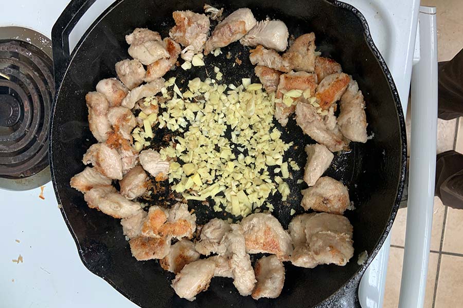 Bird meat in a pan, arranged in a circle, with garlic in the middle