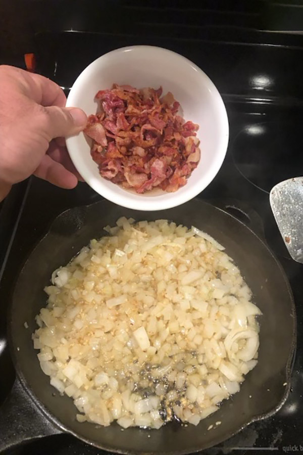 Bowl of chopped bacon strips being poured into a pan with onions