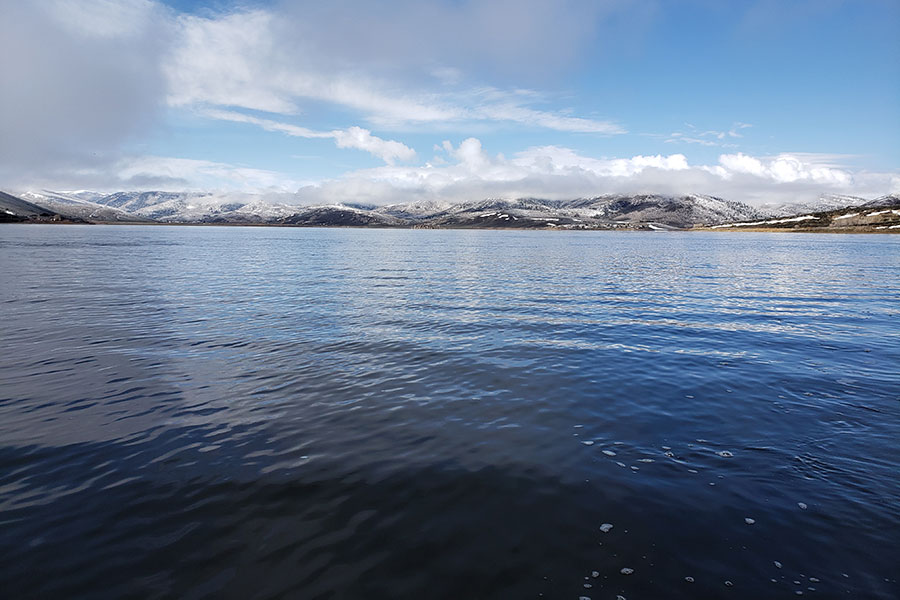 View of crystal clear water at Scofield Reservoir, surrounded by snowcapped mountains
