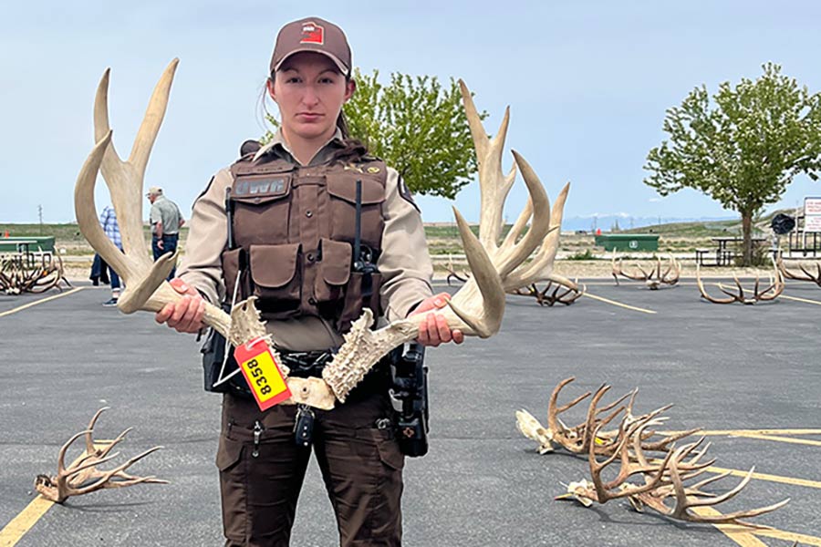 Utah DWR conservation office posing in front of a truck with shed antlers