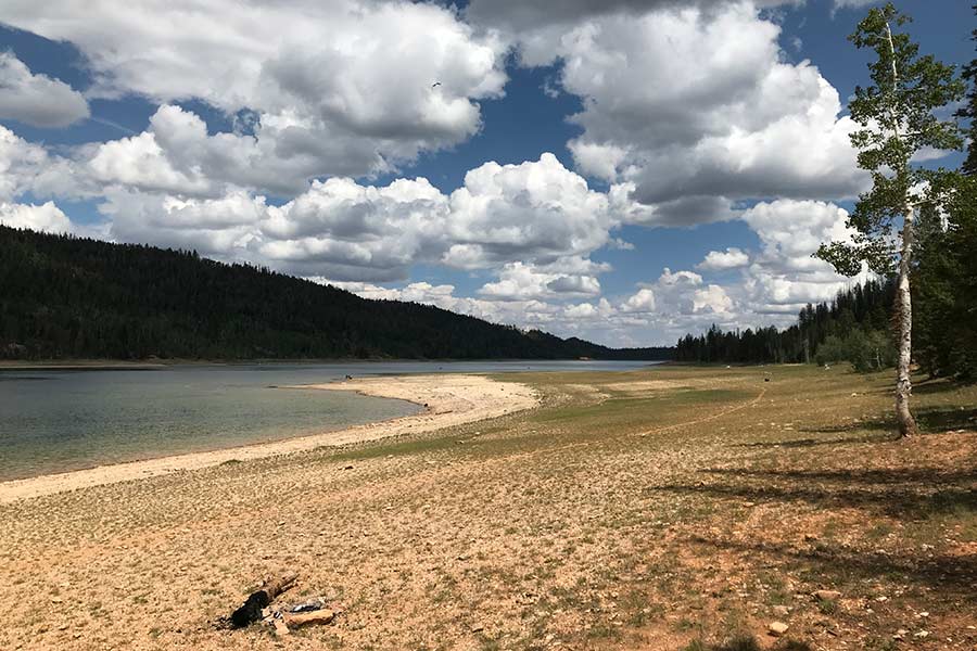 Drought-ridden Navajo Lake, with a lowered water level, under a cloudy sky