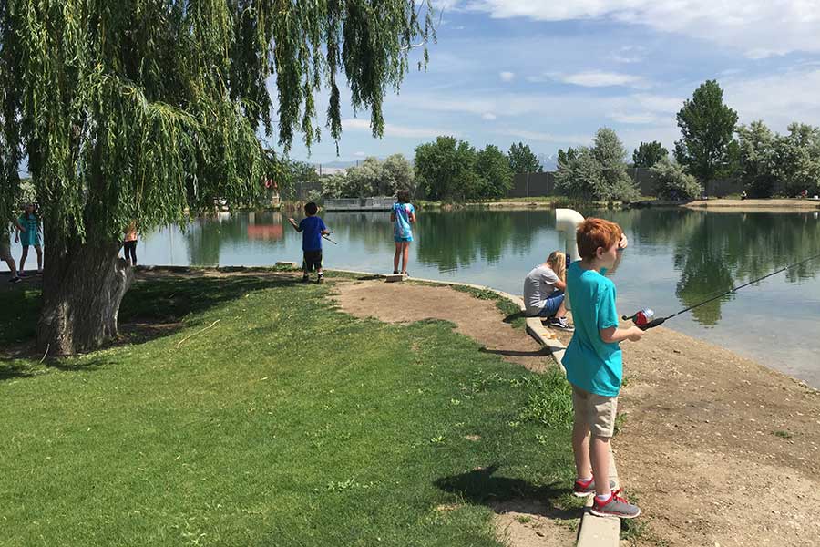 Young boy fishing at Willow Pond in Murray, below a large willow tree