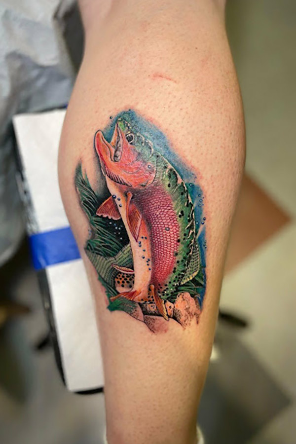 Red, green and blue tattoo of a cutthroat trout on McKay Braley's leg