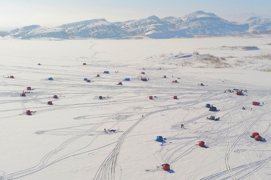 Many ice-fishing tents scattered all over the ice during a youth fishing tournament at Steinaker Reservoir