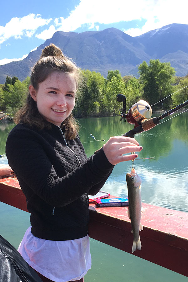 A girl holding a caught fish on a line