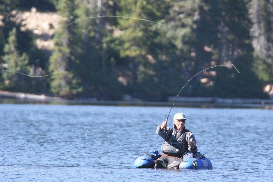 Angler in a small boat casting a fishing line into the water