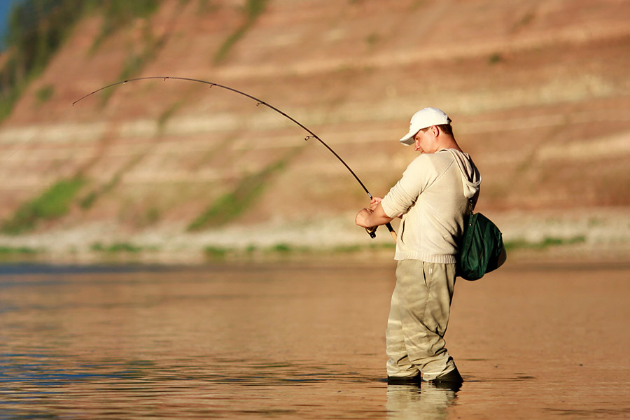 Hombre sujetando un hilo de pescar que se esfuerza por sujetar un pez