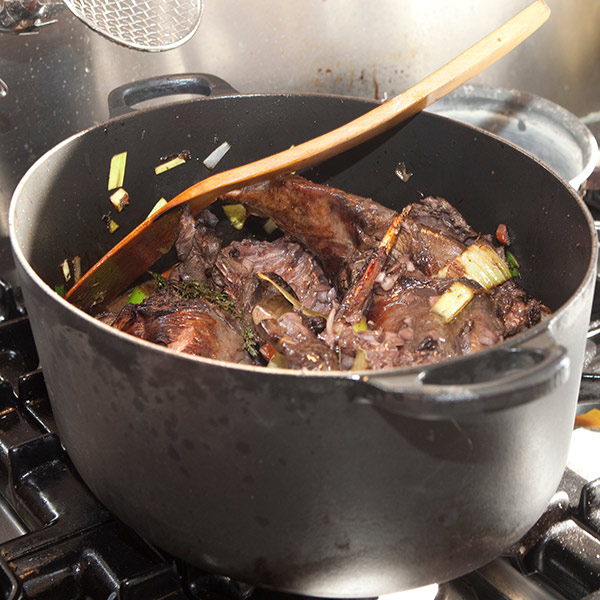 Pheasant coq au vin cooking in a pot on a stove