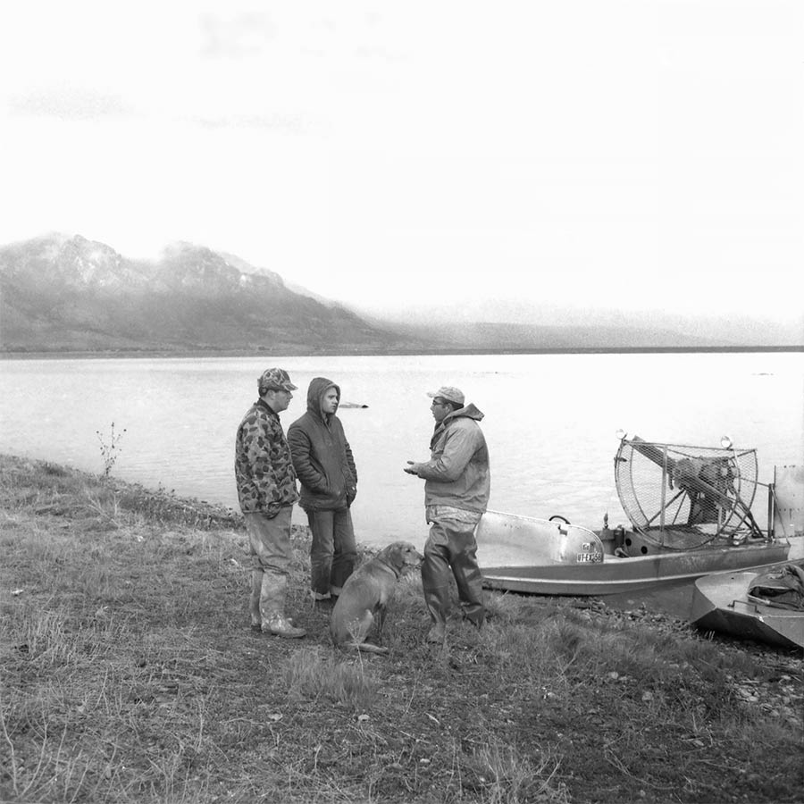 Duck hunters chatting on shore beside airboats at Ogden Bay