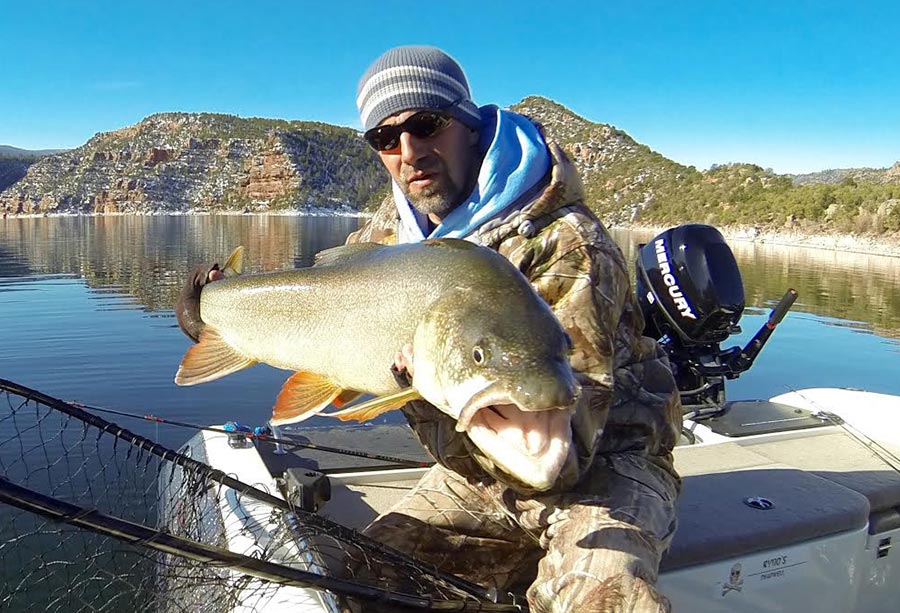 Ryan Mosley holding a large lake trout on a boat at Flaming Gorge