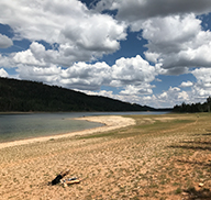 Drought-ridden Navajo Lake, with a lowered water level, under a cloudy sky