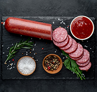 Dry sausage with fresh rosemary and spices on a stone background