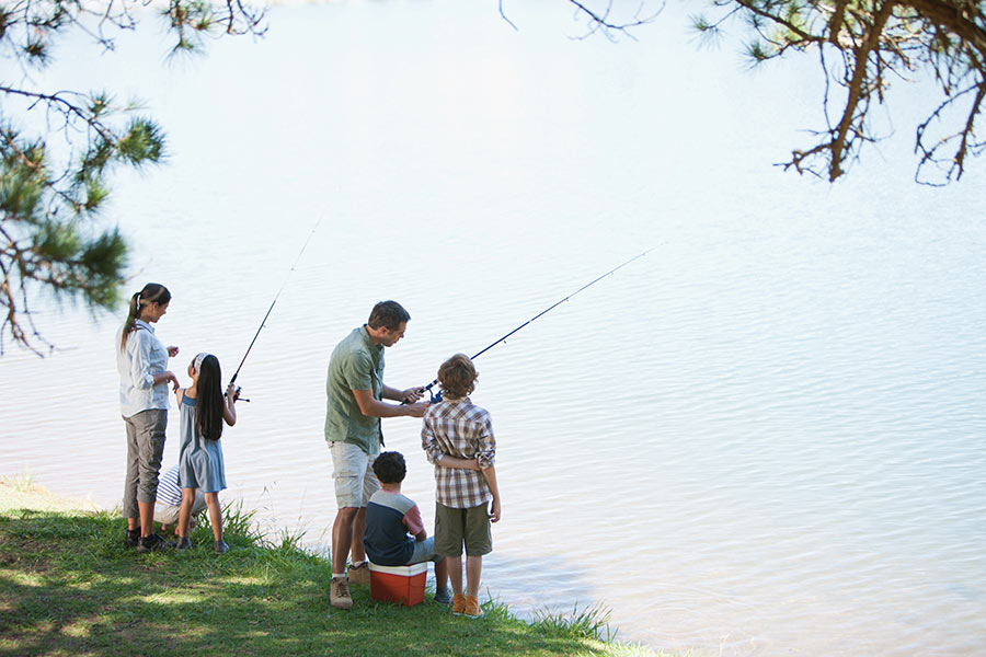 Family fishing with poles at a waterbody