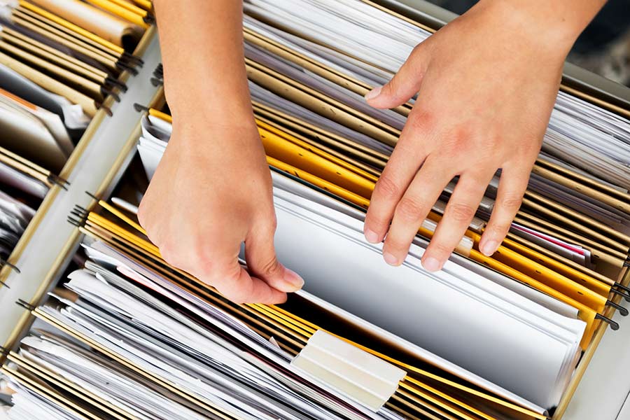 Hands pulling files out of a file cabinet