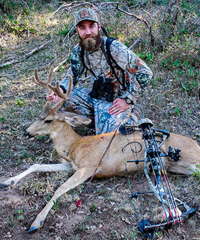 Bowhunter holding a harvested buck deer