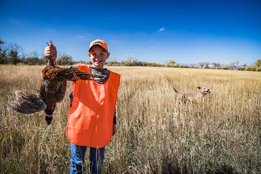 Boy holding a harvested pheasant