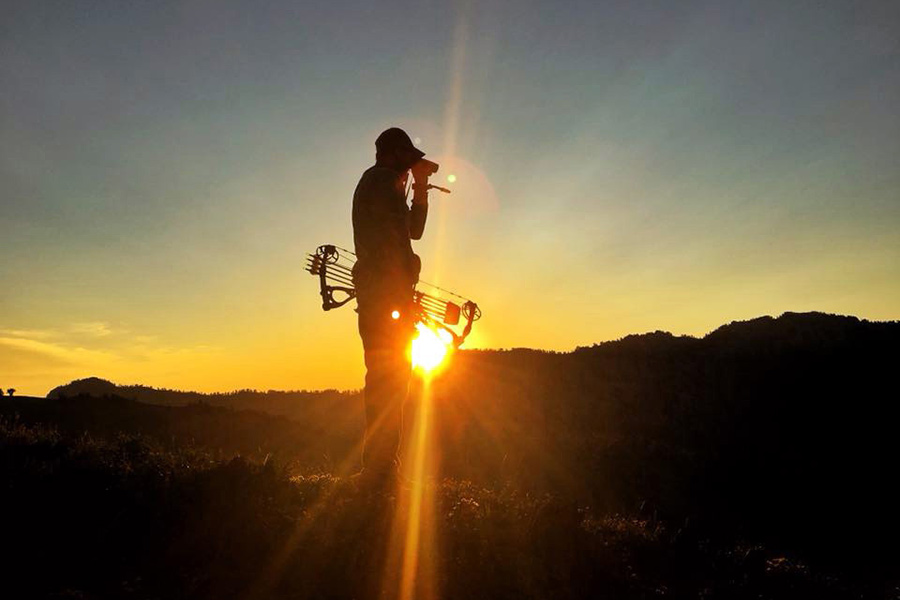 Hunter with bow and arrow at sunrise