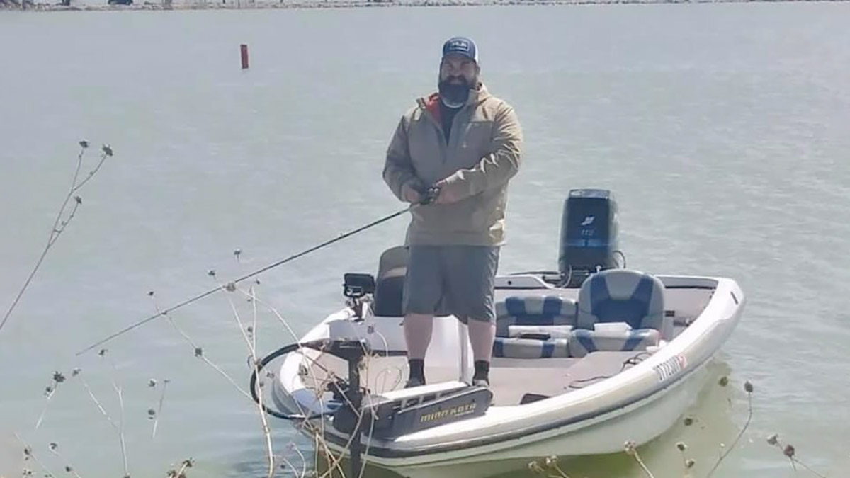 Clinton Martinez de pie en un bote, sosteniendo un hilo de pescar