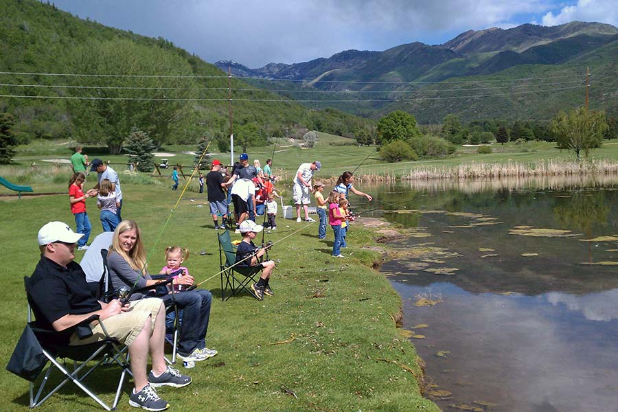 Crowd of people of all ages fishing at a pond
