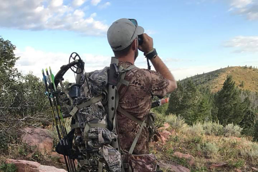 Hunter carrying archery equipment and binoculars