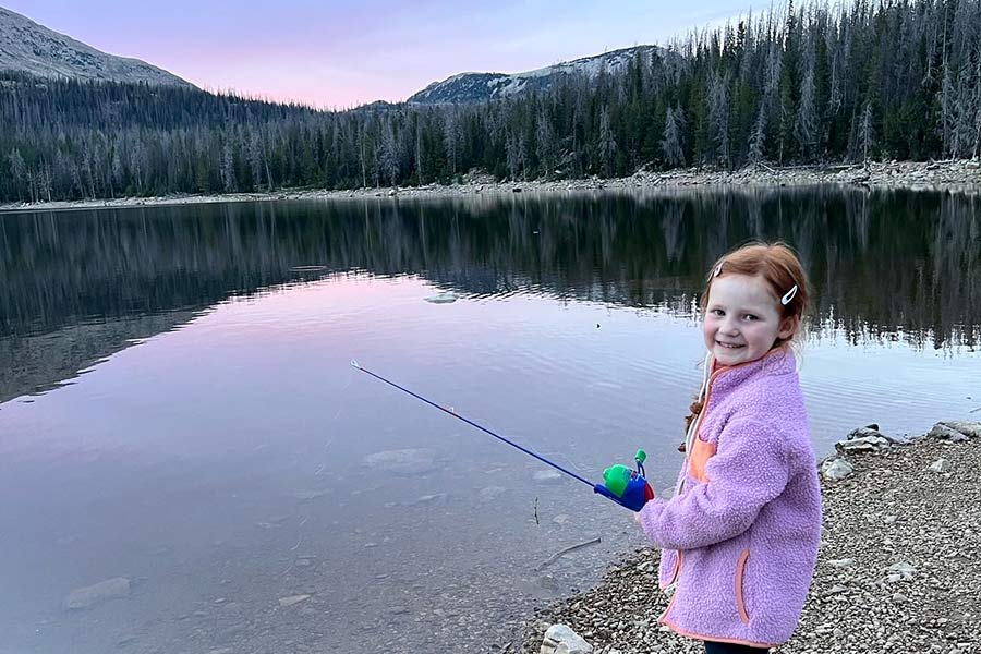 Little girl in purple coat fishing with a reel at Trial Lake