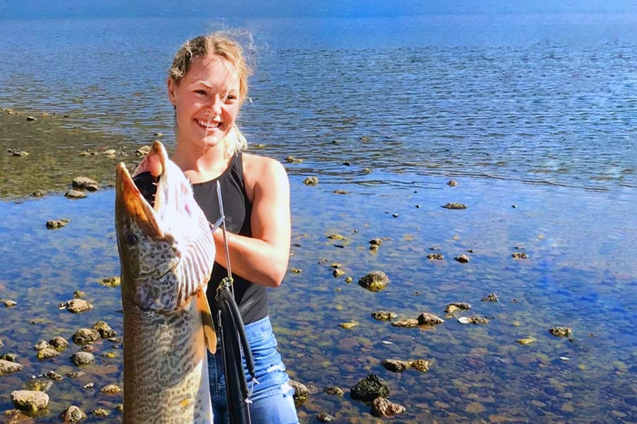 Young woman holding a tiger muskie fish, caught with a speargun