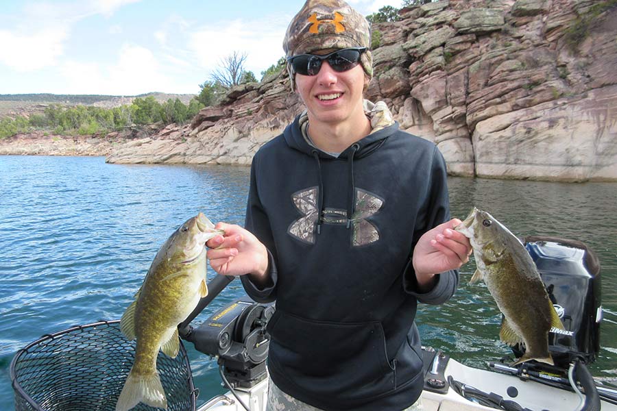 Angler holding two smallmouth bass fish caught at Flaming Gorge Reservoir