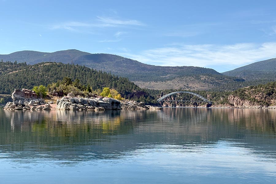 Clear water at Flaming Gorge Reservoir under a blue sky; a bridge is in the background