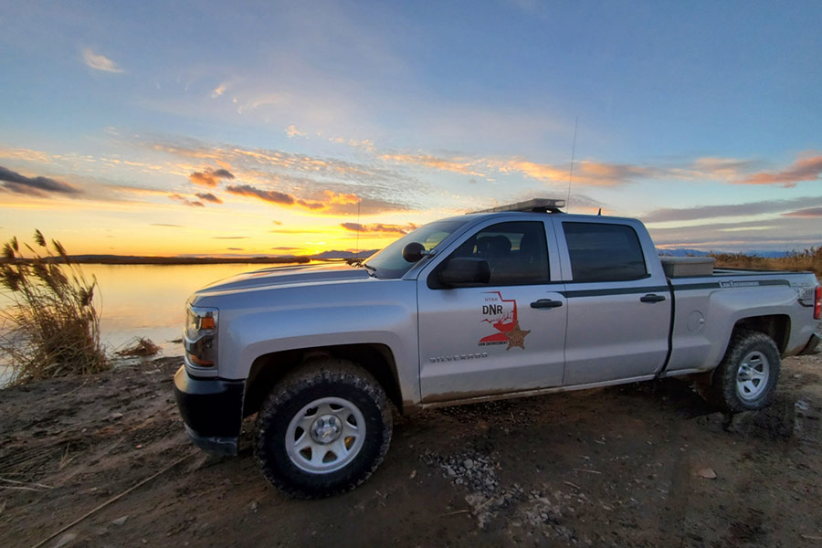 DWR conservation officers truck parked at a marsh at sunset